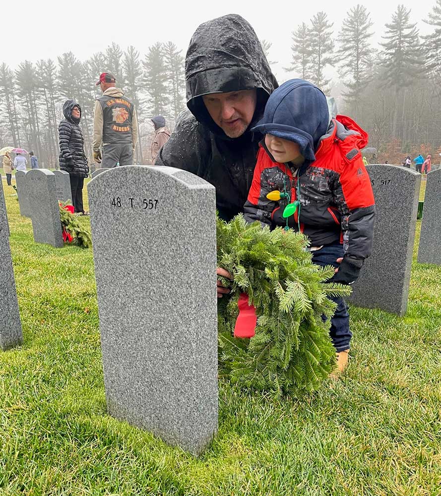 Child and father at military grave with wreath
